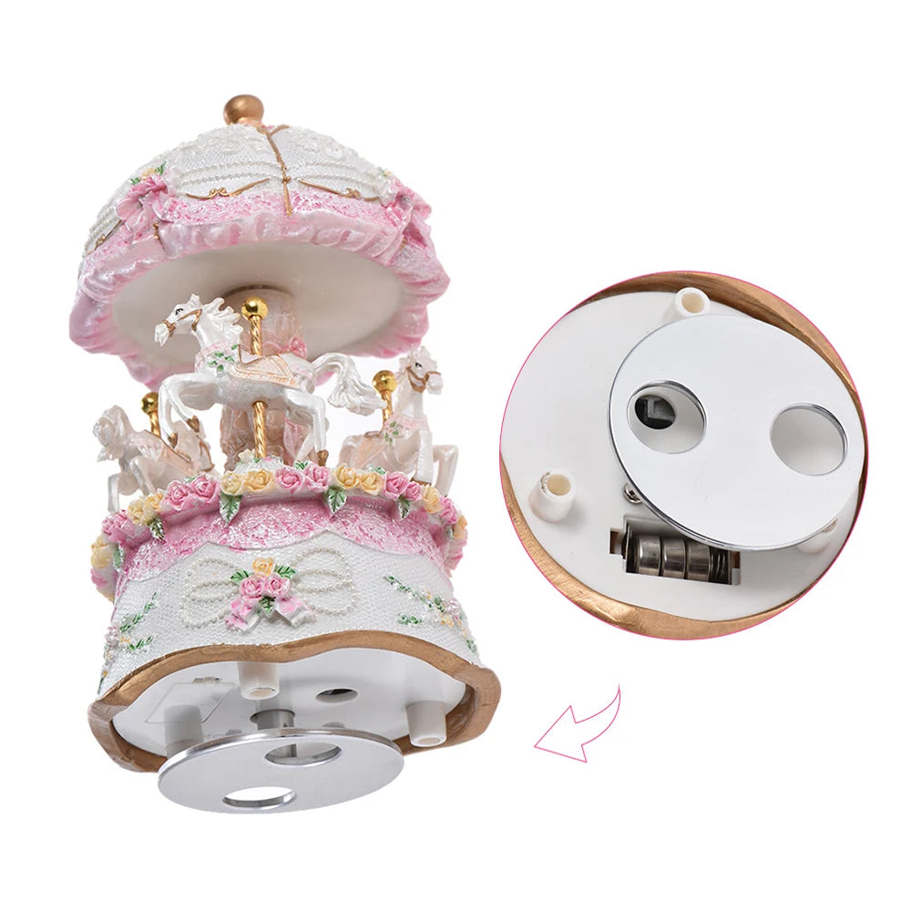 Boîte à musique carrousel blanc avec trois chevaux, décorée de roses et dentelle, avec compartiment piles visible.