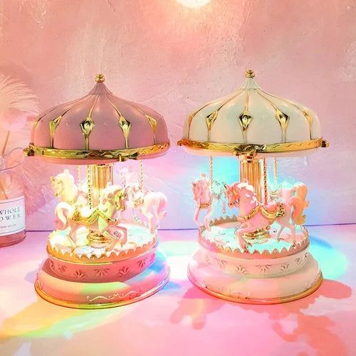 Deux boîtes à musique carrousel. La première est rose, la seconde blanc crème. Toutes deux ont des chevaux et des lumières LE
