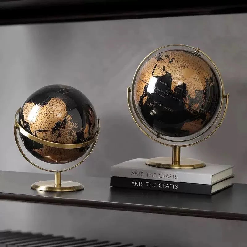Deux globes terrestres de bureau artisanaux, un noir et or et un noir et argent, sur un socle en laiton.