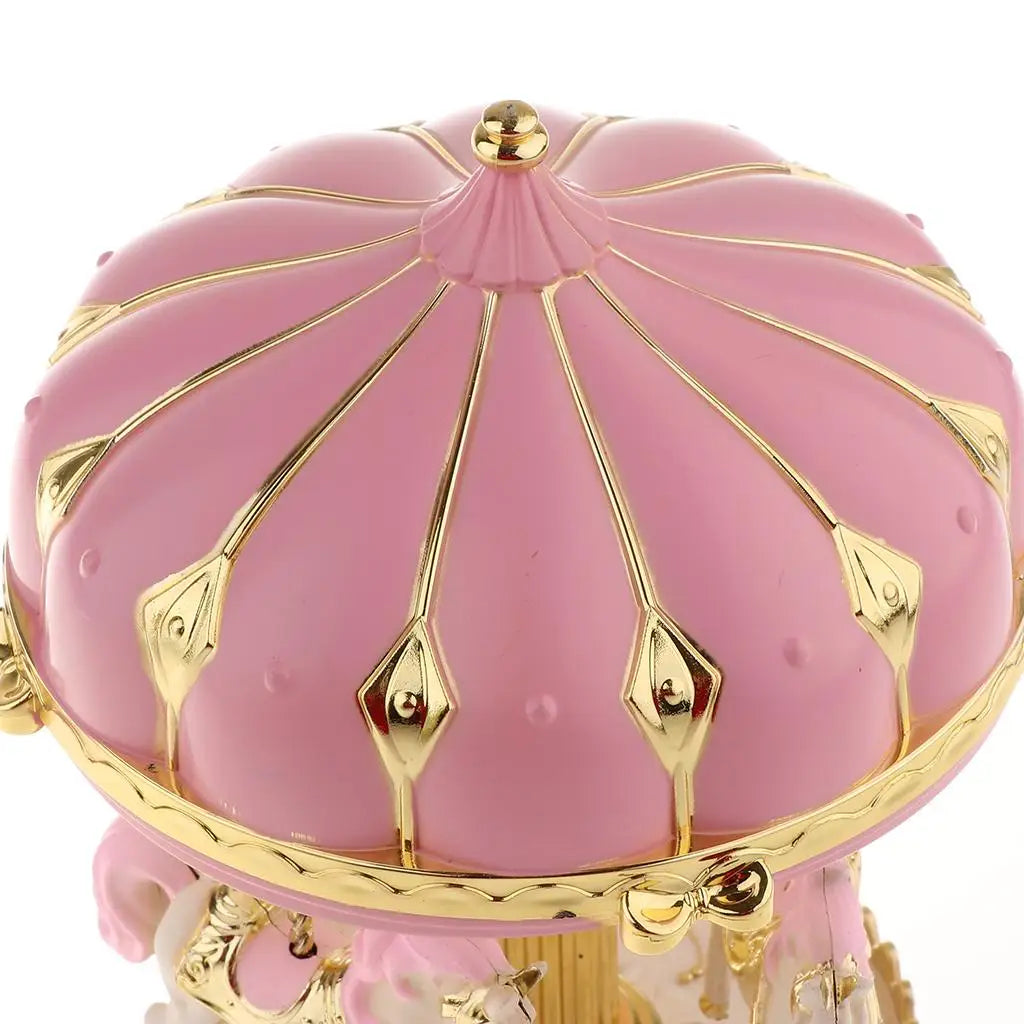 Vue rapprochée du chapiteau rose et doré d'une boîte à musique carrousel décorée de motifs géométriques peints à la main.