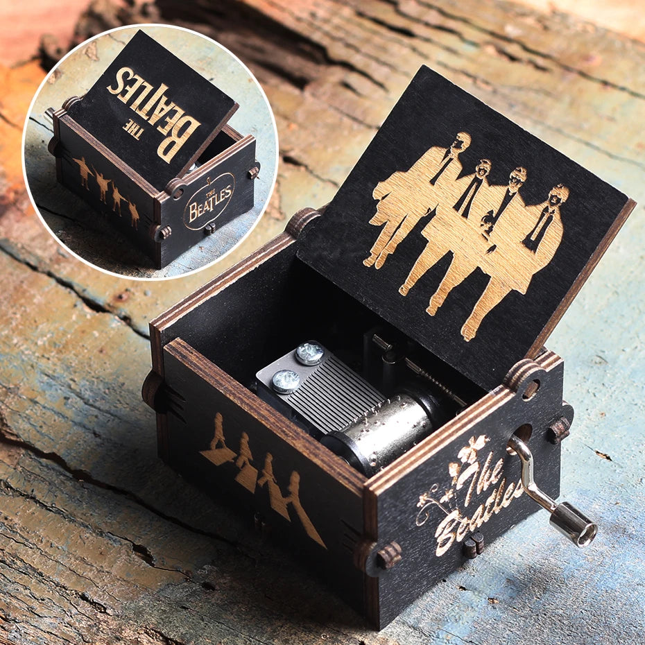 Boîte à musique en bois noir The Beatles, couvercle ouvert révélant le mécanisme et motifs dorés.