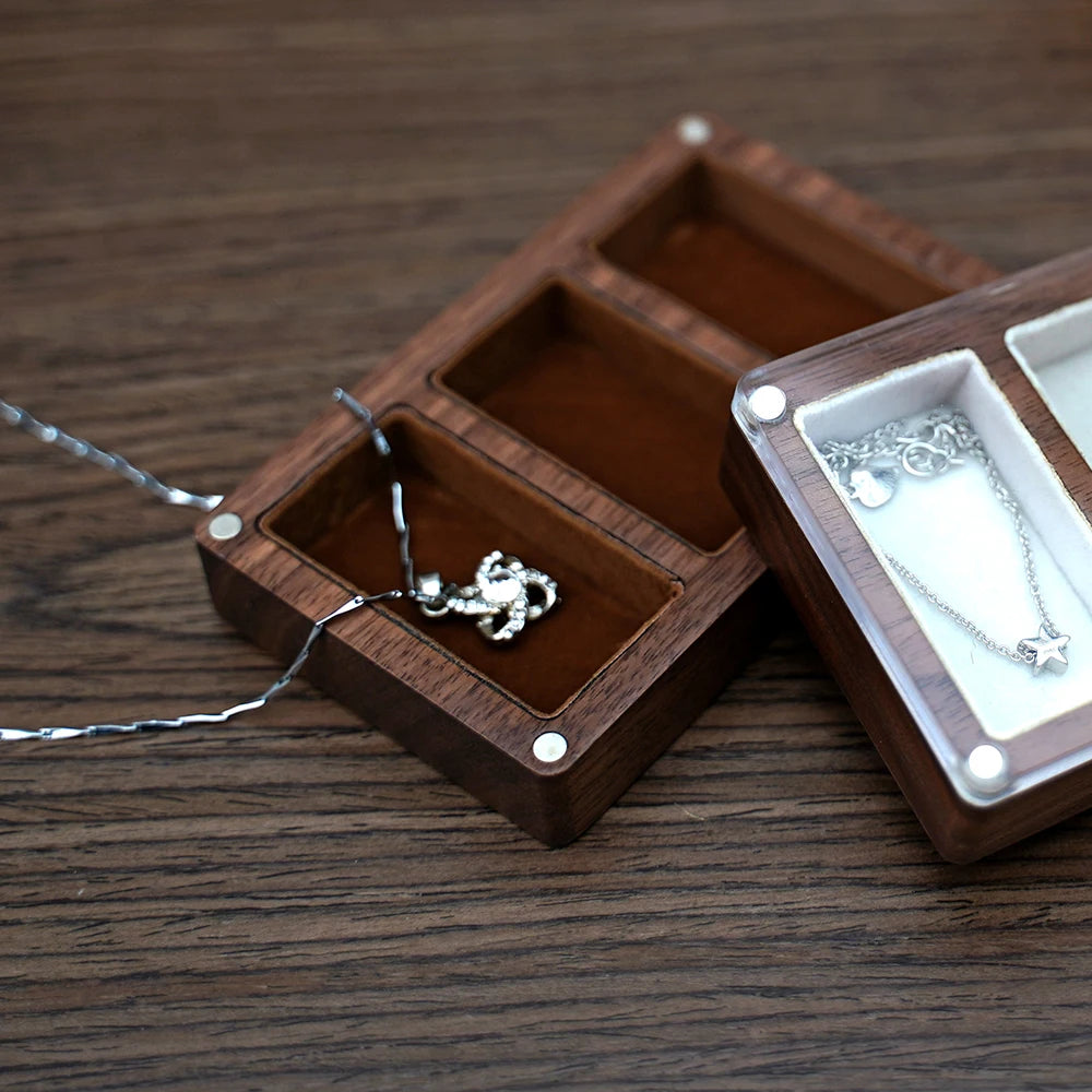 Deux petites boîtes à bijoux rectangulaires en bois, l'une ouverte montrant un collier, l'autre fermée