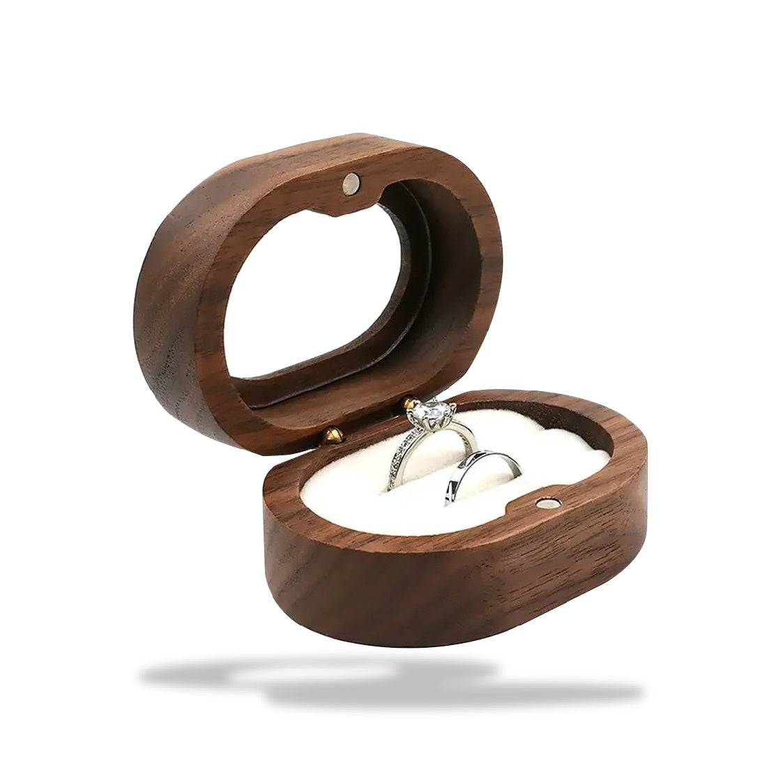 Boîte à bijoux ovale en bois brun foncé avec deux bagues argentées, une à diamant, sur un coussinet blanc.