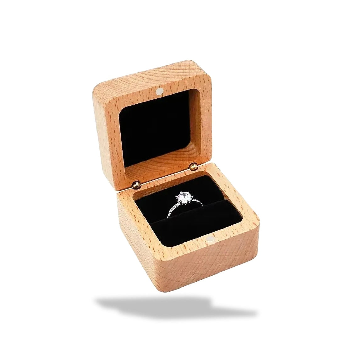Boîte à bagues en bois clair, ouverte, sur fond blanc. Un anneau en argent avec un diamant repose sur un intérieur en velours