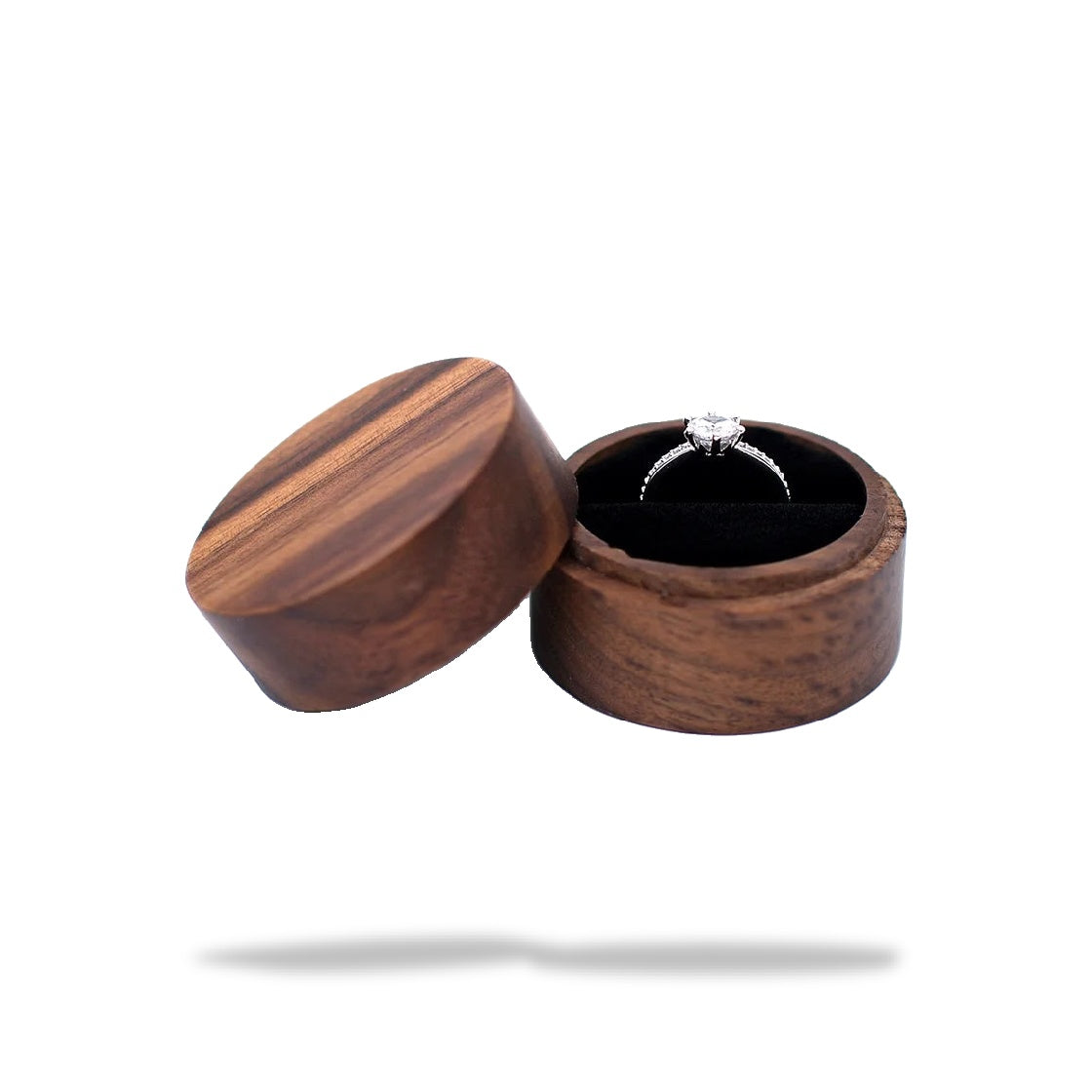 Boîte à bague de fiançailles ronde en bois sombre, ouverte. Un anneau avec un diamant solitaire est visible à l'intérieur sur