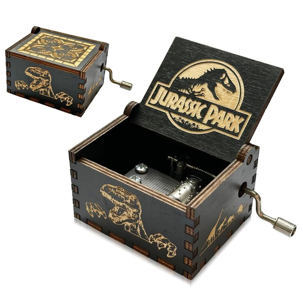 Boîte à musique en bois noire, motif Jurassic Park, avec manivelle et mécanisme doré apparent. Motif dinosaure sur le côté.