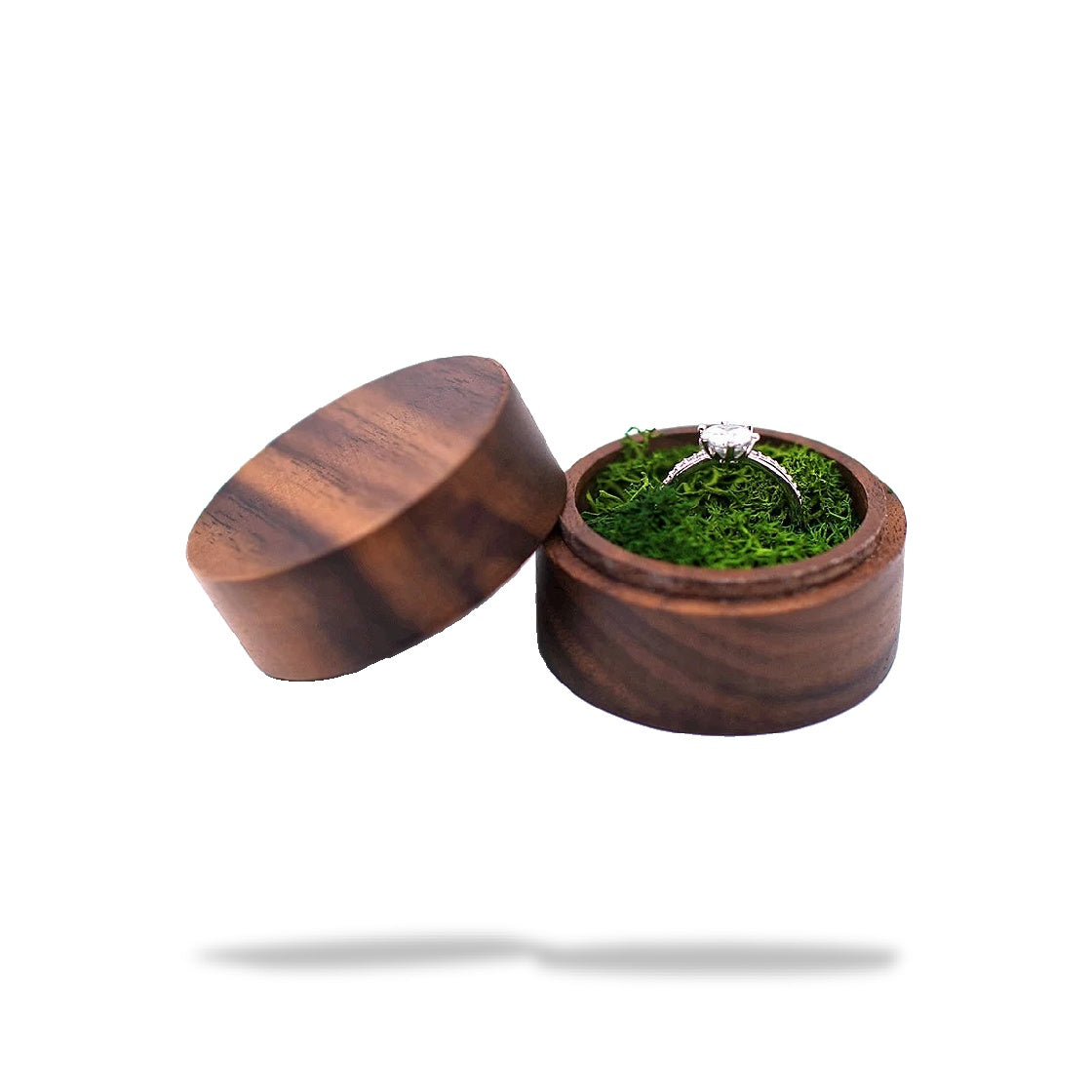 Boîte à bague de fiançailles ronde en bois marron foncé, légèrement ouverte, contenant une bague sur de la mousse verte.