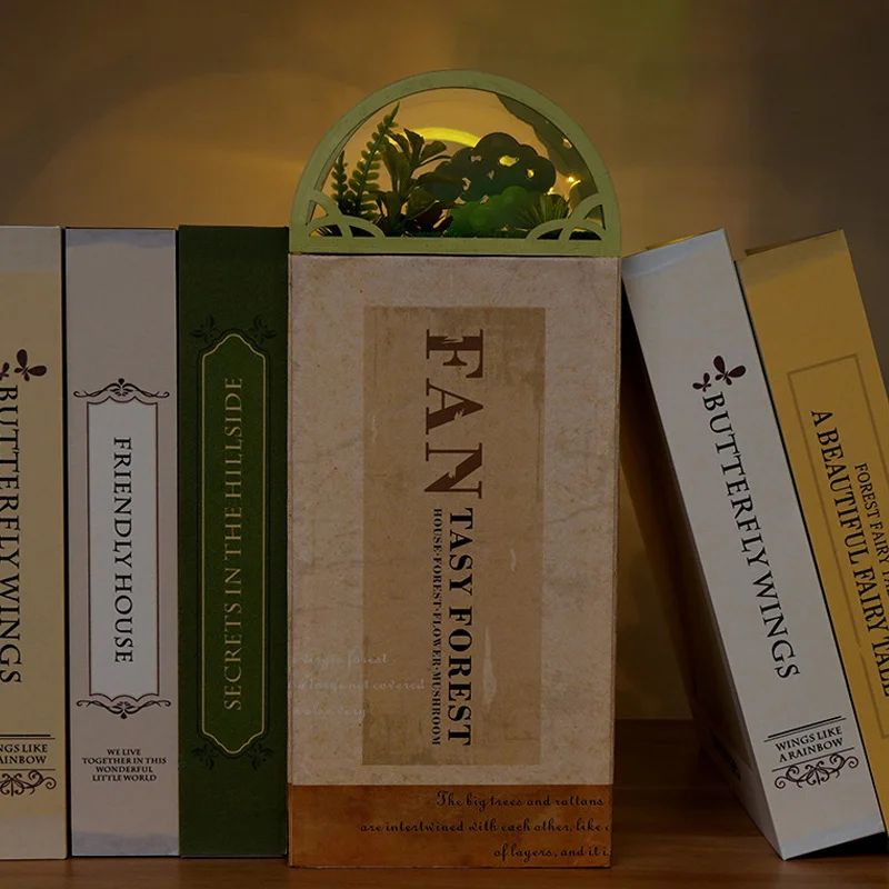 Kit serre-livres avec des lumières LED, un arc vert et des éléments de feuillage. Posé entre des livres.