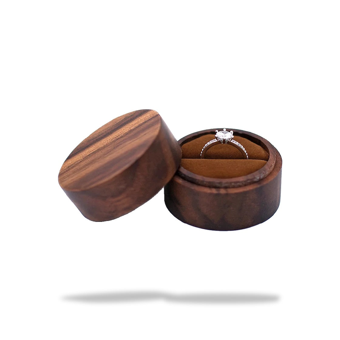 Boîte à bague de fiançailles ronde en bois sombre, ouverte. Une bague en argent avec un diamant est placée sur le coussinet i