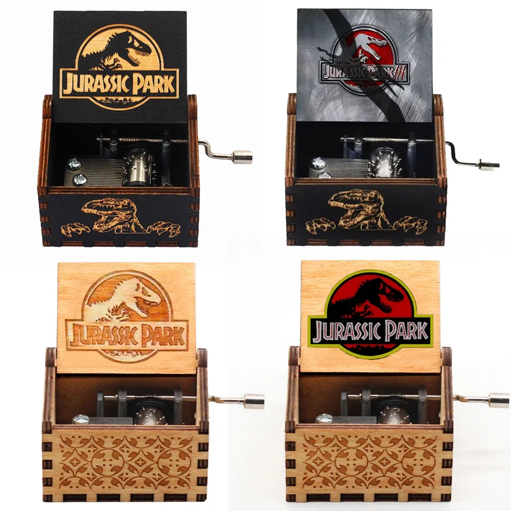 Quatre boîtes à musique ouvertes sur un fond blanc, affichant des logos Jurassic Park variés et des motifs.