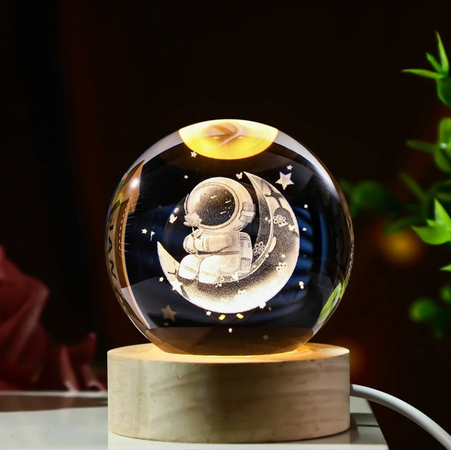 Veilleuse LED avec sphère en verre et base en bois clair. Un astronaute sur la lune est gravé en 3D à l'intérieur.