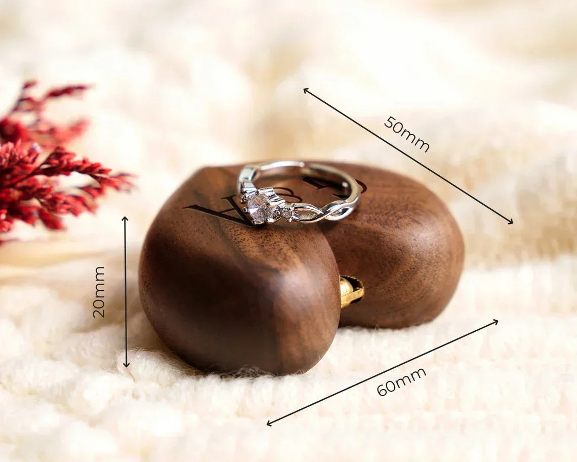 Boîte à bague en bois de noyer en forme de cœur, gravée, de 60x50x20 mm, avec une bague en argent ornée.