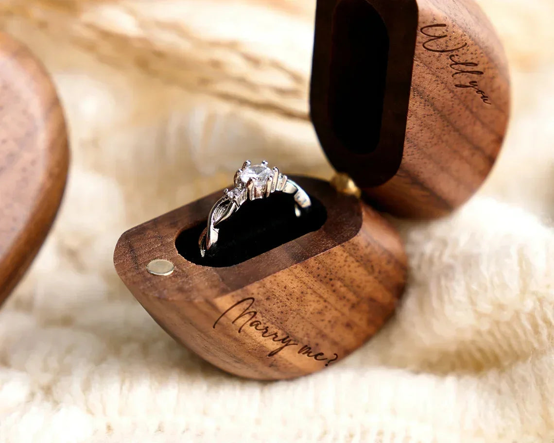 Boîte à bague cœur en bois de noyer ouverte, avec une bague en argent ornée d'un diamant et gravée