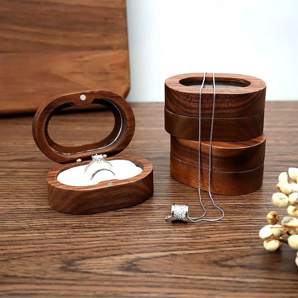 Boîte à bijoux ovale en bois de couleur marron foncé, ouverte, avec un anneau serti de diamants à l'intérieur. Trois boîtes s