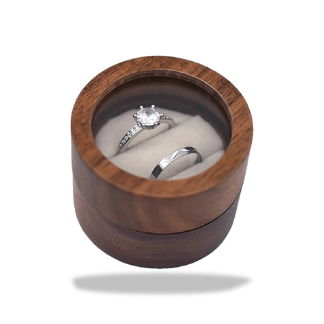 Boîte à bagues de fiançailles cylindrique en bois brun foncé, avec un couvercle transparent révélant deux fentes en tissu bei