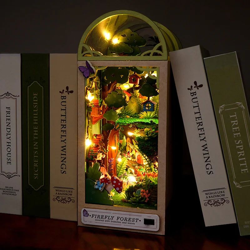 Serre-livres en bois avec scène de forêt miniature illuminée par des LED, intégrant des arbres et une maison.