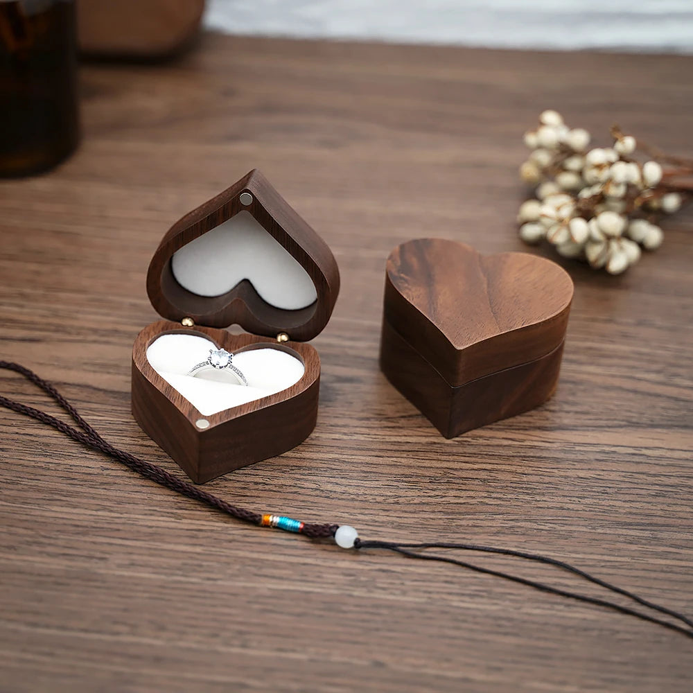 Deux boîtes à bijoux en bois de noyer en forme de cœur, une ouverte avec une bague, l'autre fermée.