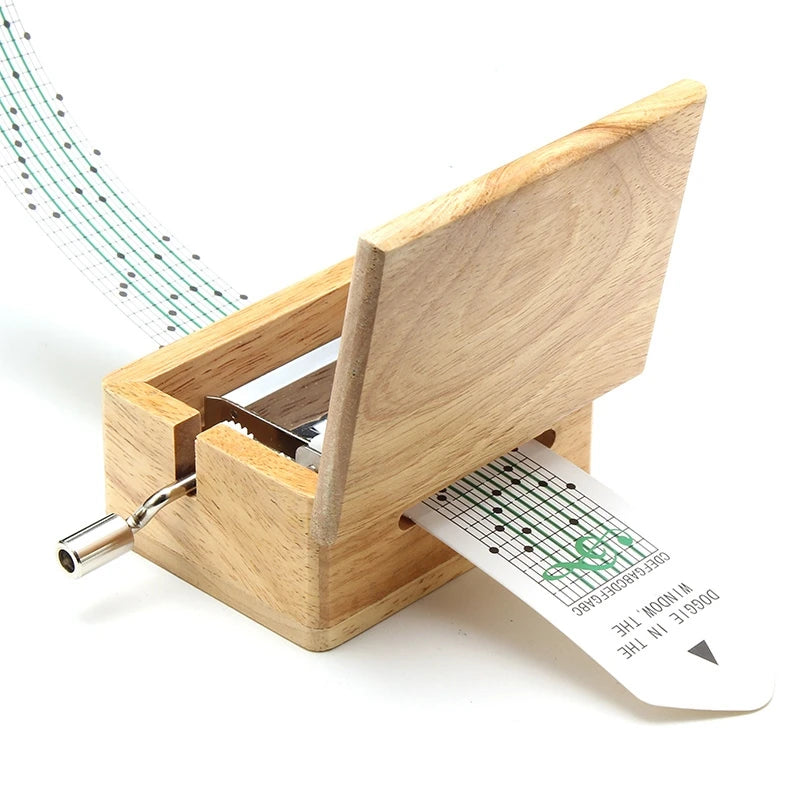 Boîte à musique en bois clair avec couvercle ouvert, mécanisme interne apparent et bande de papier perforée insérée.