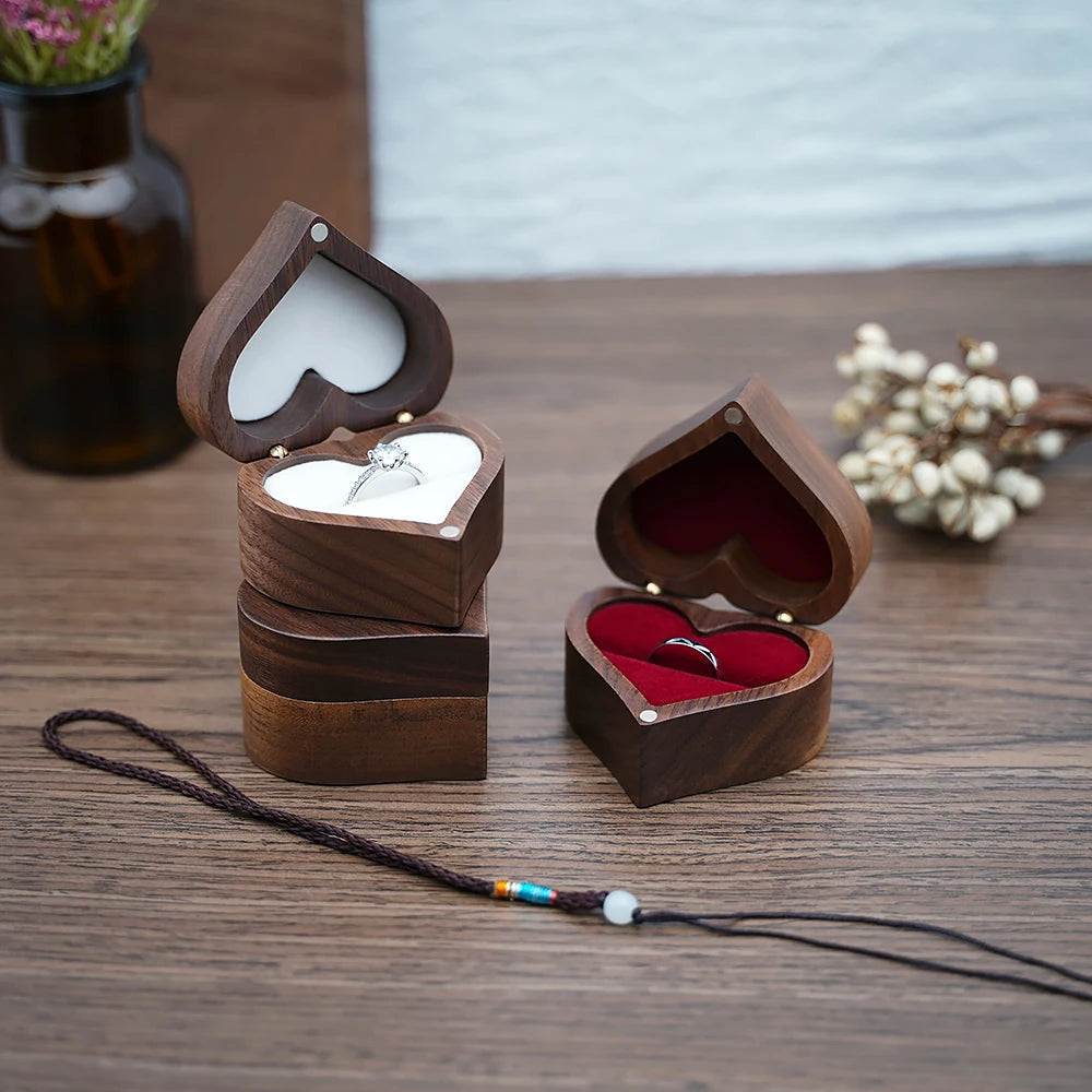 Deux boîtes à bijoux en bois de noyer en forme de cœur, l'une ouverte avec un anneau, l'autre vide.