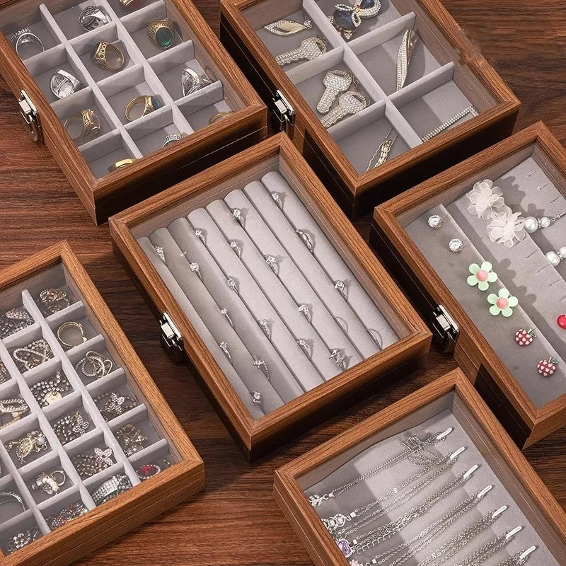 Vue d'ensemble de cinq boîtes à bijoux en bois de noyer marron avec couvercles en verre, affichant des compartiments organisé