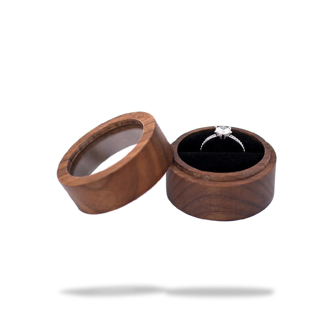 Boîte à bague de fiançailles ronde en bois marron foncé ouverte, avec un coussinet en tissu noir et une bague argentée avec u
