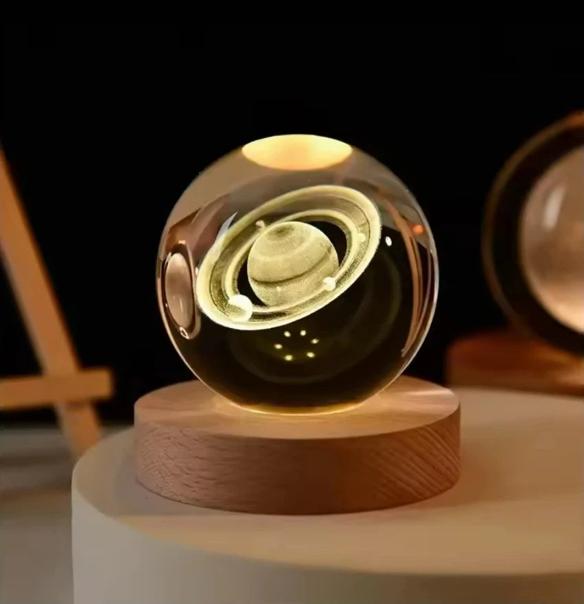 Veilleuse LED avec une sphère en verre affichant le modèle 3D de Saturne, reposant sur une base en bois.