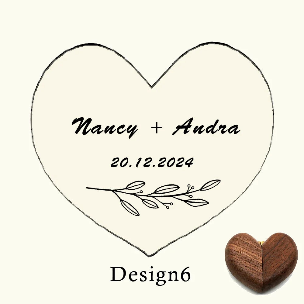 Boîte à bague en bois de noyer en forme de cœur, avec gravure personnalisée des noms "Nancy + Andra" et la date "20.12.2024".