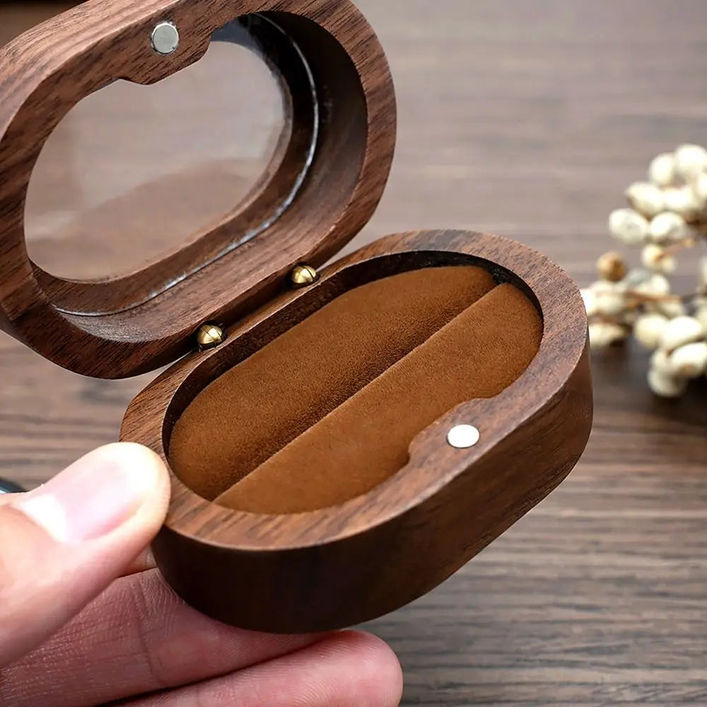 Boîte à bijoux ovale ouverte en bois foncé, avec intérieur en velours brun et un dessus vitré.