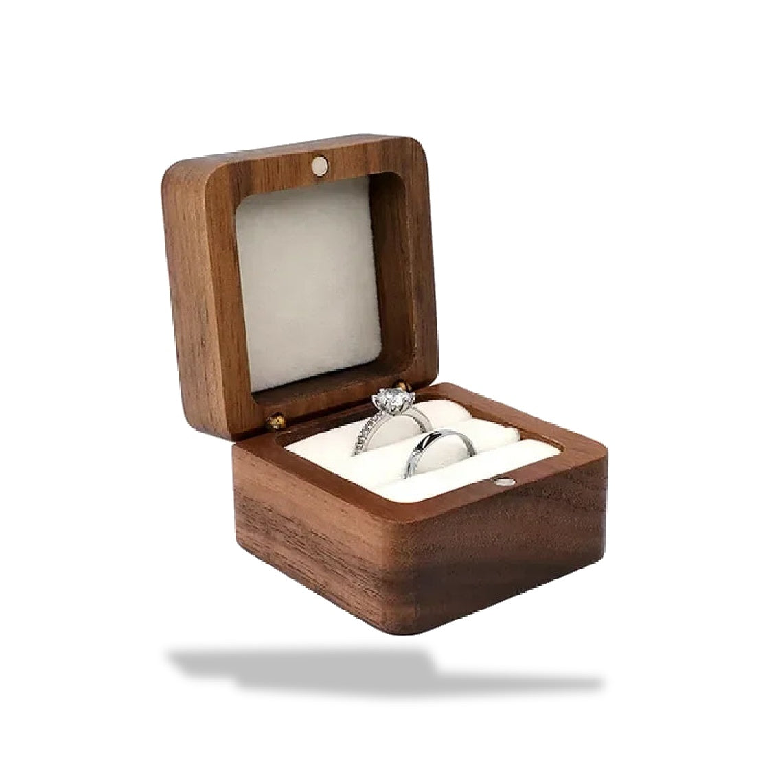 Boîte à bagues en bois foncé ouverte, garnie d'une éponge blanche et contenant deux bagues.