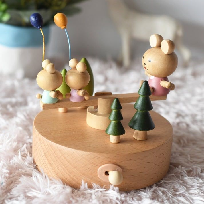Boîte à musique en bois de hêtre de 13,5 cm, figurines de lapins sur une balançoire avec arbres et ballons.