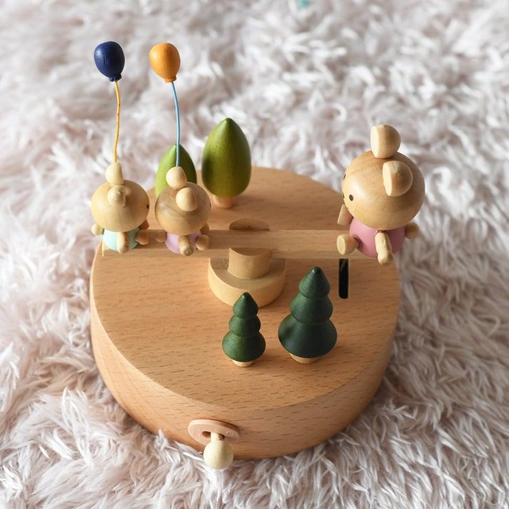 Boîte à musique en bois de hêtre naturel avec trois oursons en figurines, une balançoire et des arbres décoratifs. Un tiroir