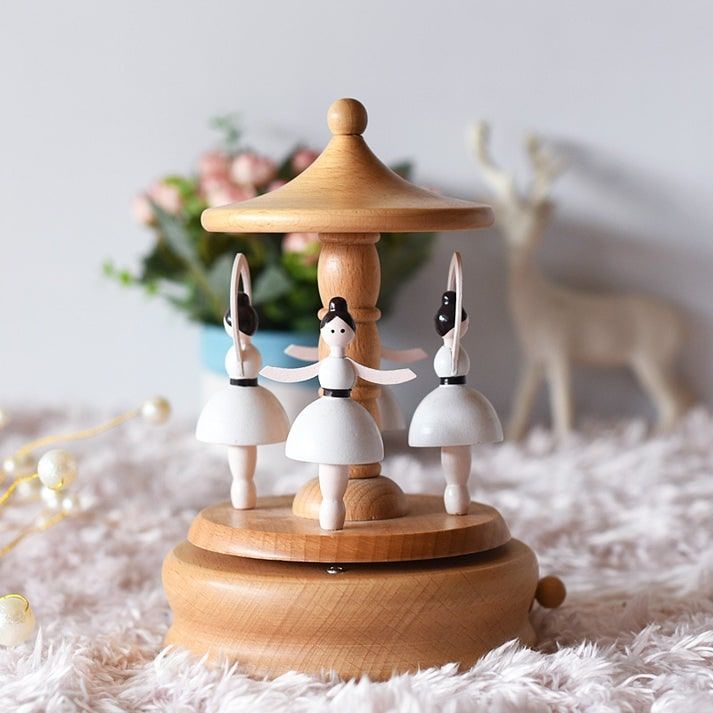 Boîte à musique en hêtre clair avec trois ballerines blanches et noires rotatives sur un socle.