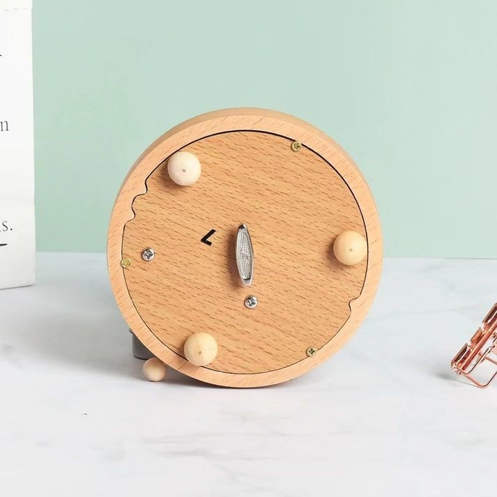 Vue de dessous d'une boîte à musique carrousel enfant en hêtre. On voit le mécanisme métallique.