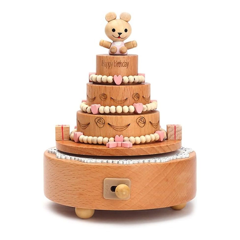 Boîte à musique en bois clair en forme de gâteau d'anniversaire à plusieurs étages. Un ours en bois est au sommet.