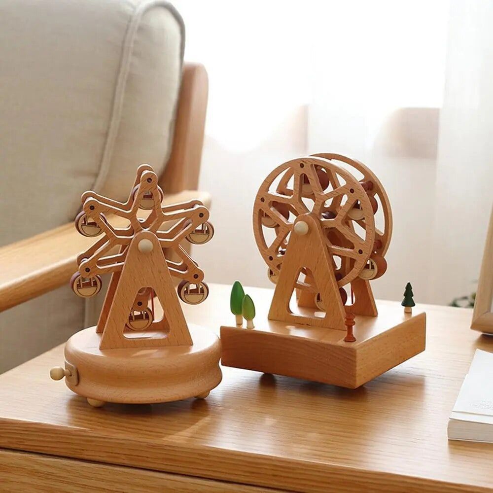 Deux boîtes à musique en bois de hêtre, des grandes roues de manège, sur une table en bois.
