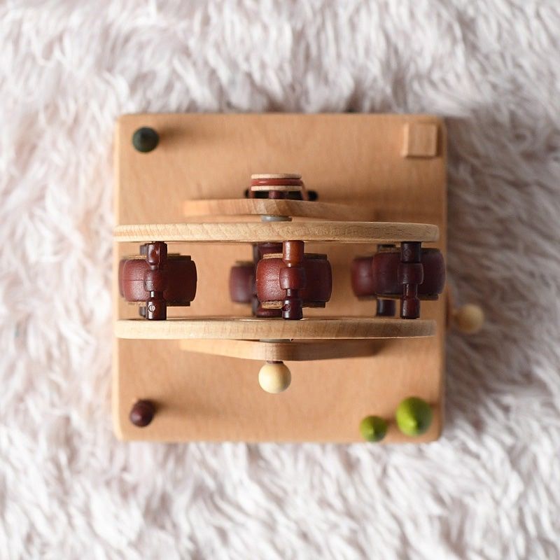 Boîte à musique en bois de hêtre représentant une grande roue avec cabines marron, sur fond duveteux.