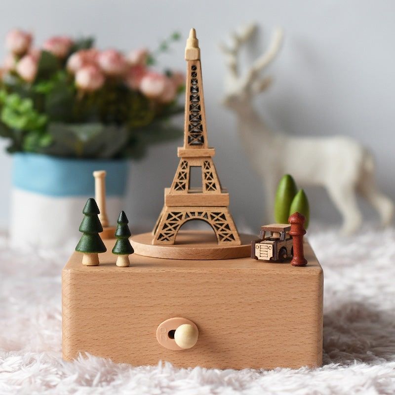 Boîte à musique en hêtre, avec une Tour Eiffel gravée et d'autres figurines comme des sapins et une voiture.