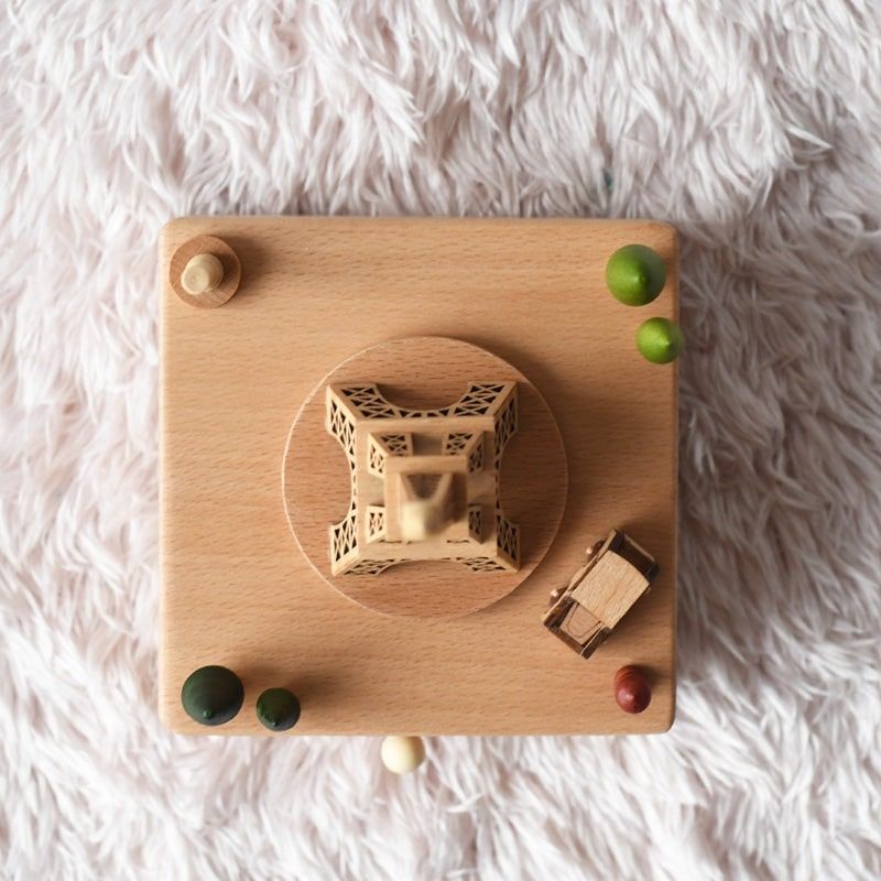 Boîte à musique en hêtre, Tour Eiffel ajourée et voiturette en bois sur une plateforme rotative.