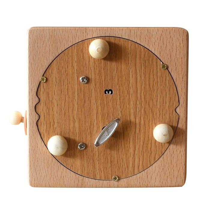 Boîte à musique carrée en hêtre, face avant vue de dessus. Cadran en bois avec manivelle et quatre billes en bois claires.