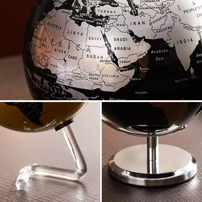 Globe terrestre décoratif avec carte grise sur fond noir, monté sur un support en métal argenté. Vue rapprochée.