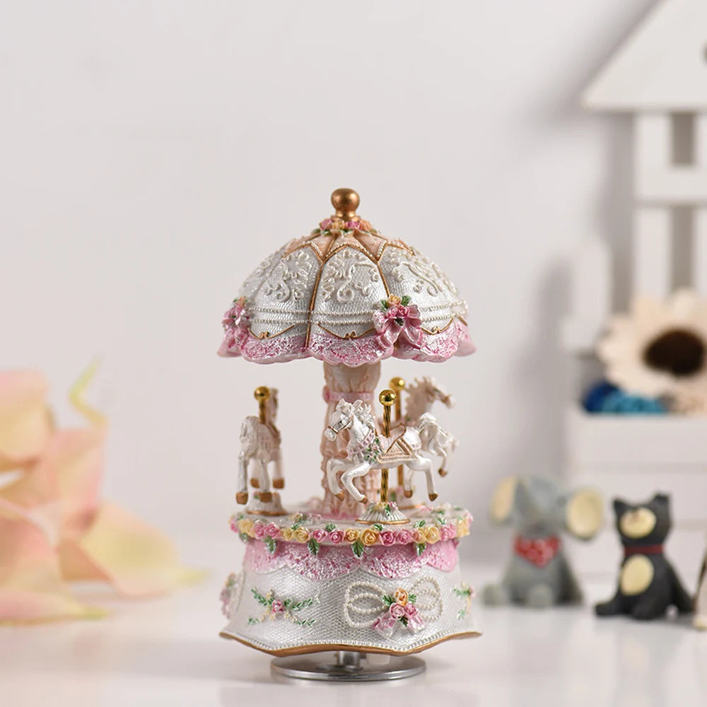 Boîte à musique carrousel blanc et rose en résine avec 3 chevaux, parapluie décoré et motif floral.