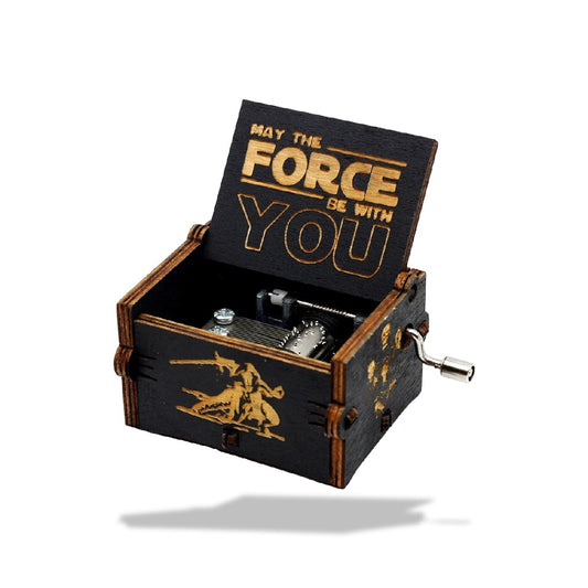 Boîte à musique en bois noire, ouverte, avec engrenages visibles, et inscription "May The Force Be With You" sur le couvercle