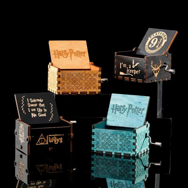 Quatre boîtes à musique Harry Potter ouvertes, en bois clair, noir et bleu, avec manivelles et motifs variés.
