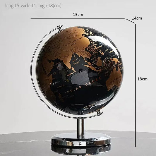 Globe terrestre rotatif avec continents dorés et océans noirs, sur un socle et un axe métalliques.