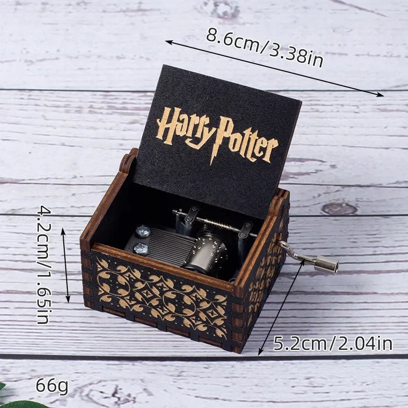 Boîte à musique Harry Potter en bois sombre, couvercle ouvert avec logo et mécanisme visible, manivelle sur le côté.
