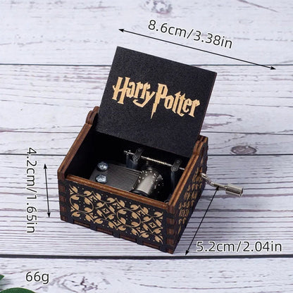 Boîte à musique Harry Potter en bois sombre, couvercle ouvert avec logo et mécanisme visible, manivelle sur le côté.
