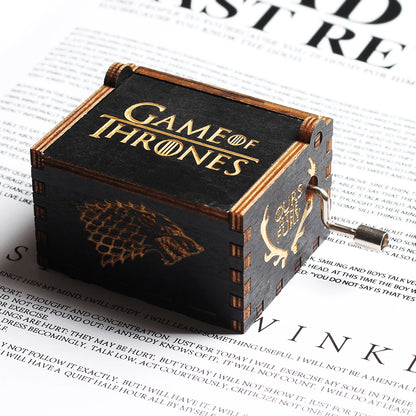 Boîte à musique en bois noire, motif Loup et cerf dorés, et texte "Game of Thrones" visible sur le dessus.