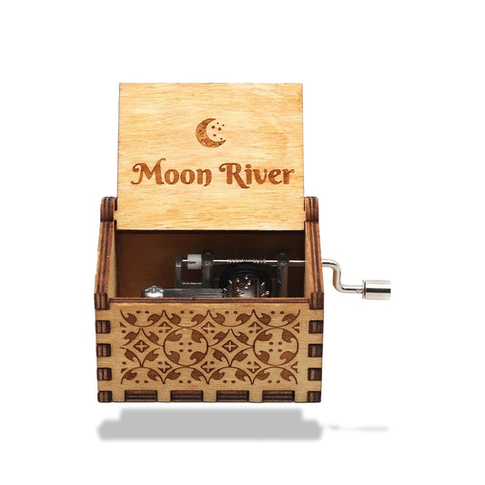 Boîte à musique en bois clair avec une manivelle latérale. Le couvercle ouvert affiche 'Moon River' et une lune.