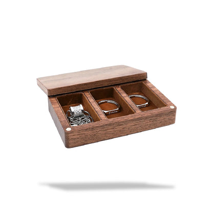 Boîte à bijoux en bois marron avec couvercle ouvert, présentant trois compartiments doublés de tissu velours marron. Le premi