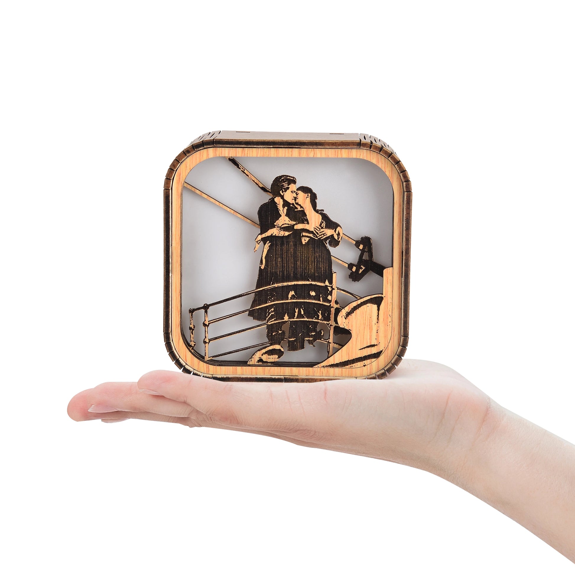 Boîte à musique veilleuse faite main en bois clair, de 10x10x8cm. Elle représente un couple s'embrassant sur un bateau.